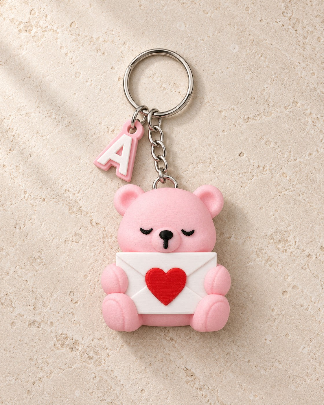 Initial Bear Keyring on a pale limestone plinth, soft studio light