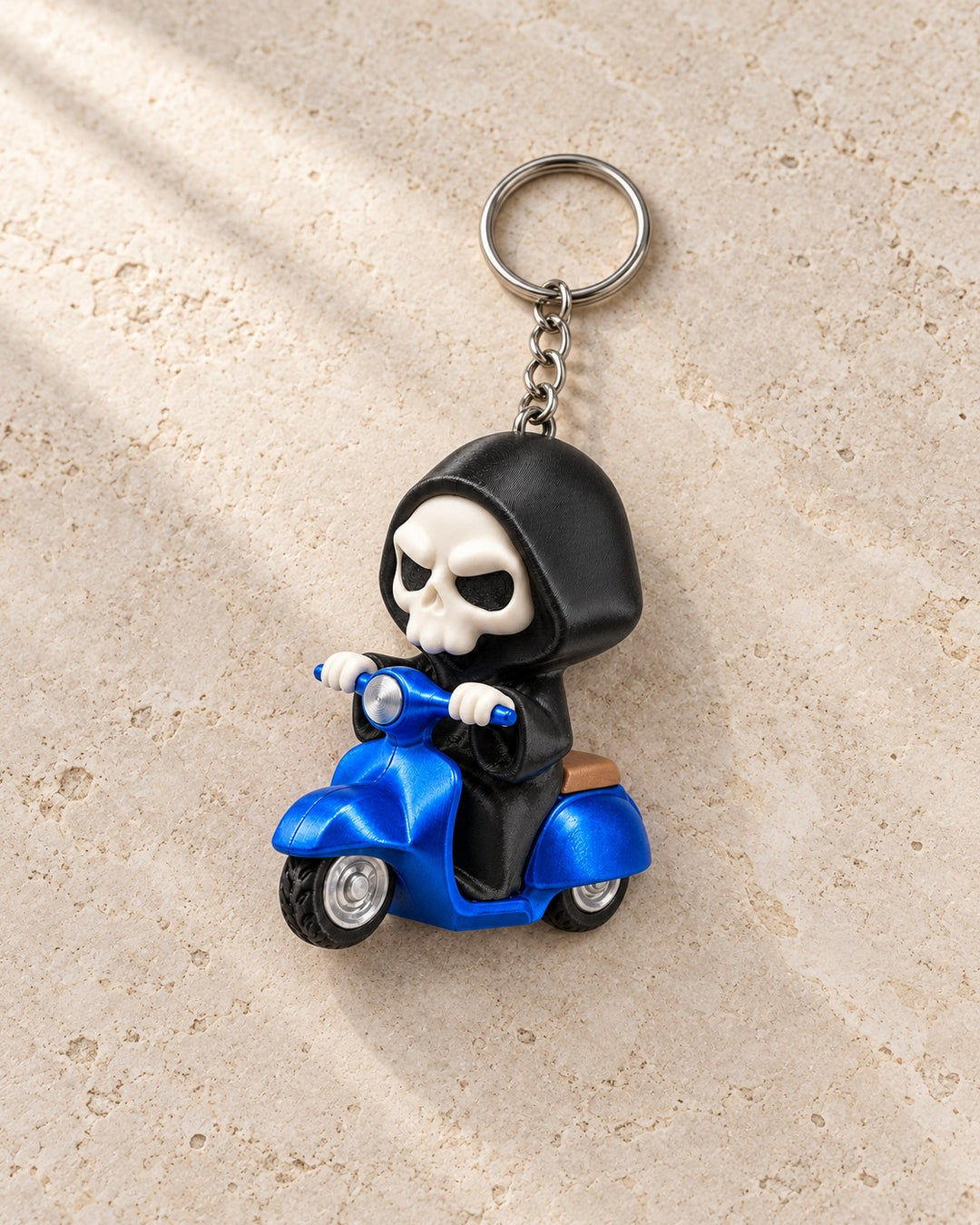 Grim Rider Keyring: A hooded reaper on a blue retro scooter, with ring and chain