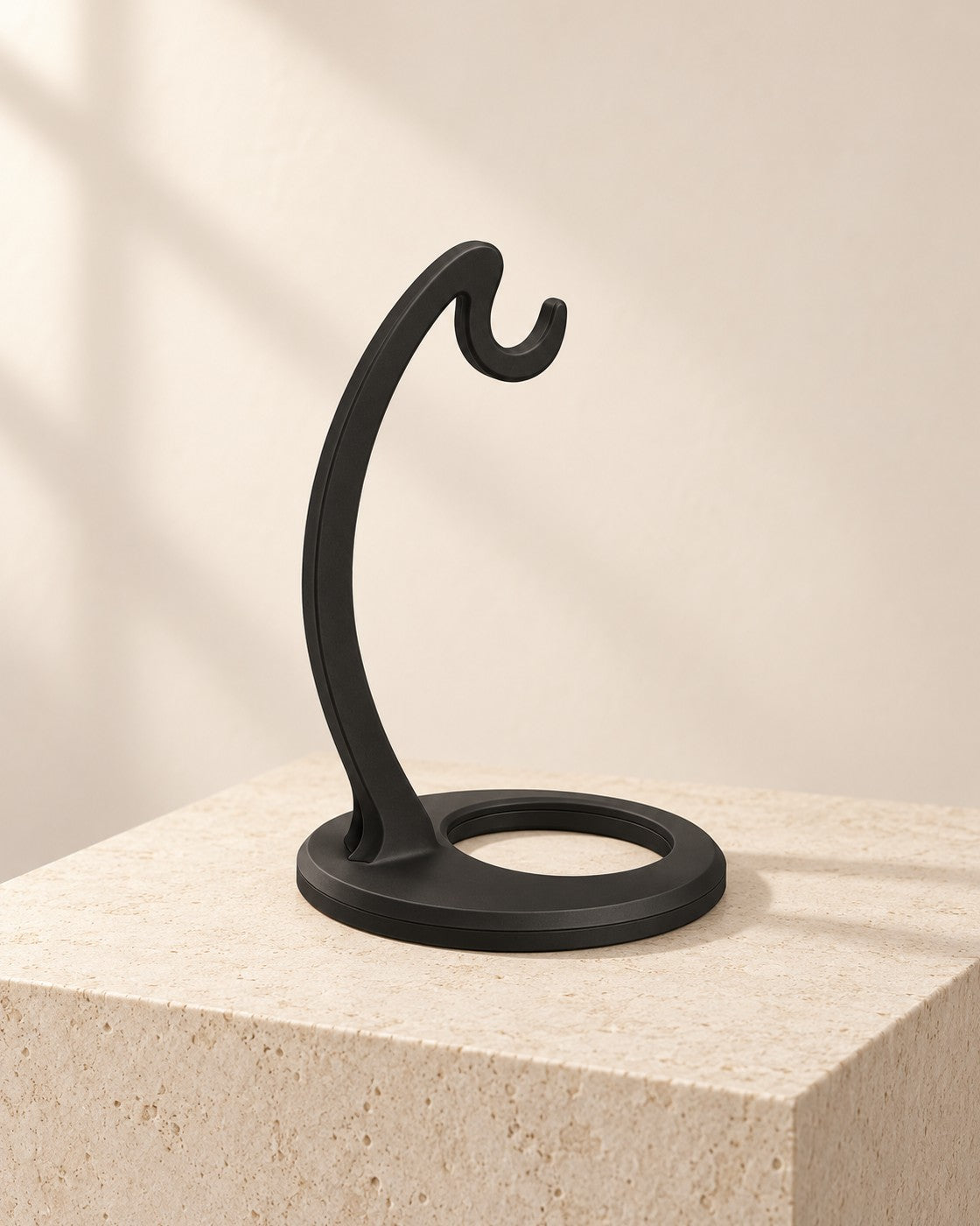 Matte Black Banana Hanger on a pale limestone plinth, soft studio light