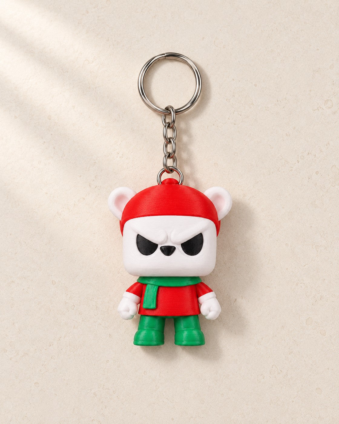 Grumpy Bear Keyring on a pale limestone plinth, soft studio light