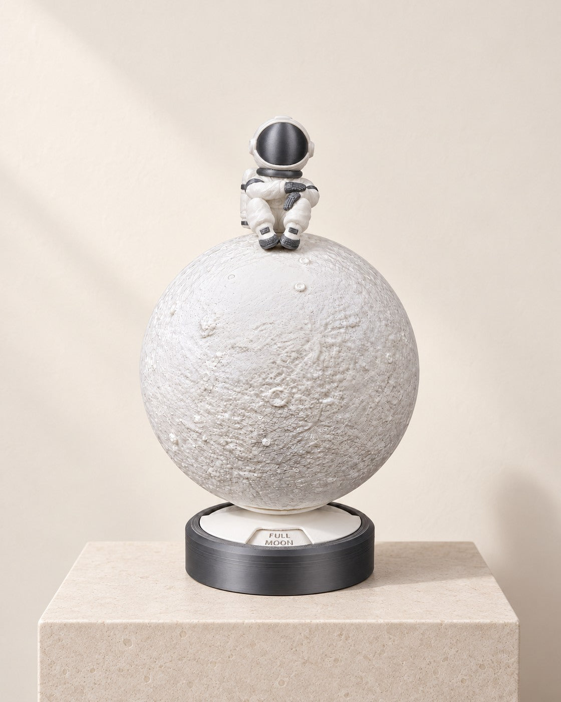 Moon Phase Astronaut Lamp on a pale limestone plinth, soft studio light