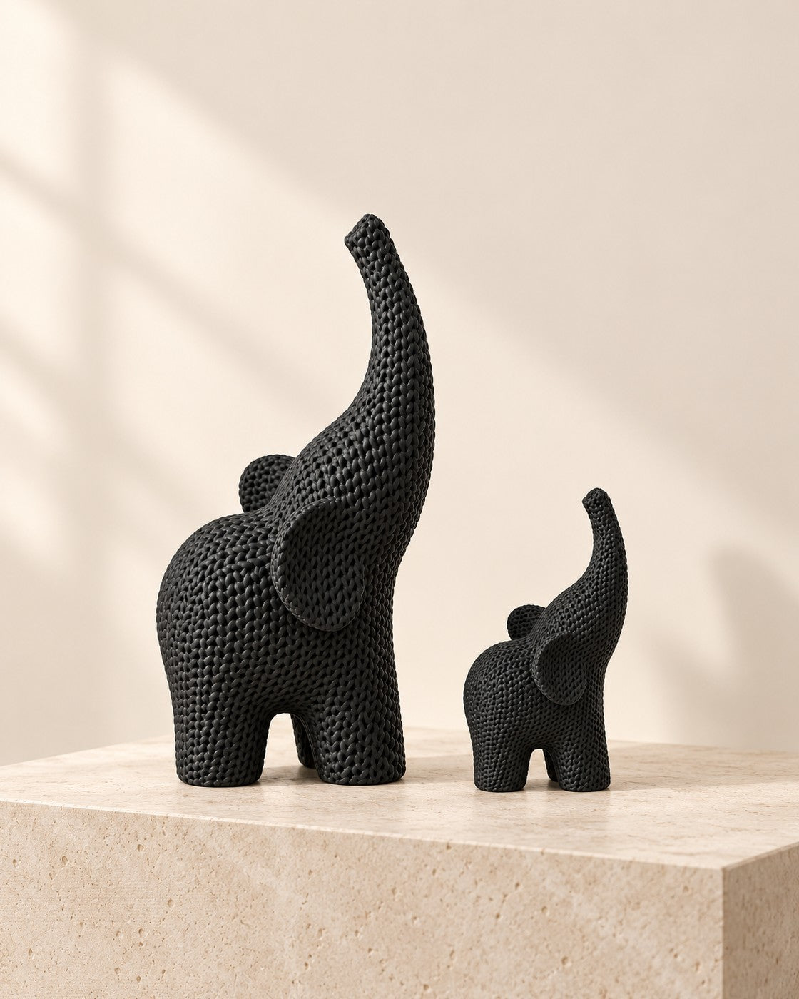 Knitted Elephant Pair on a pale limestone plinth, soft studio light