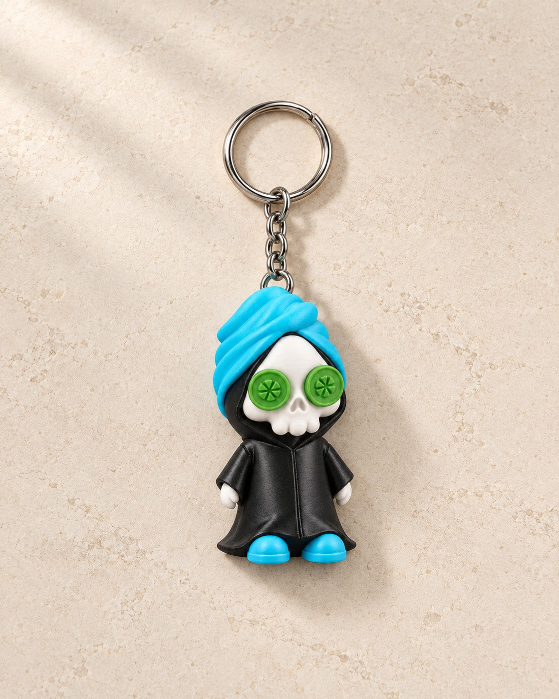 Reap in Peace Keyring on a pale limestone plinth, soft studio light