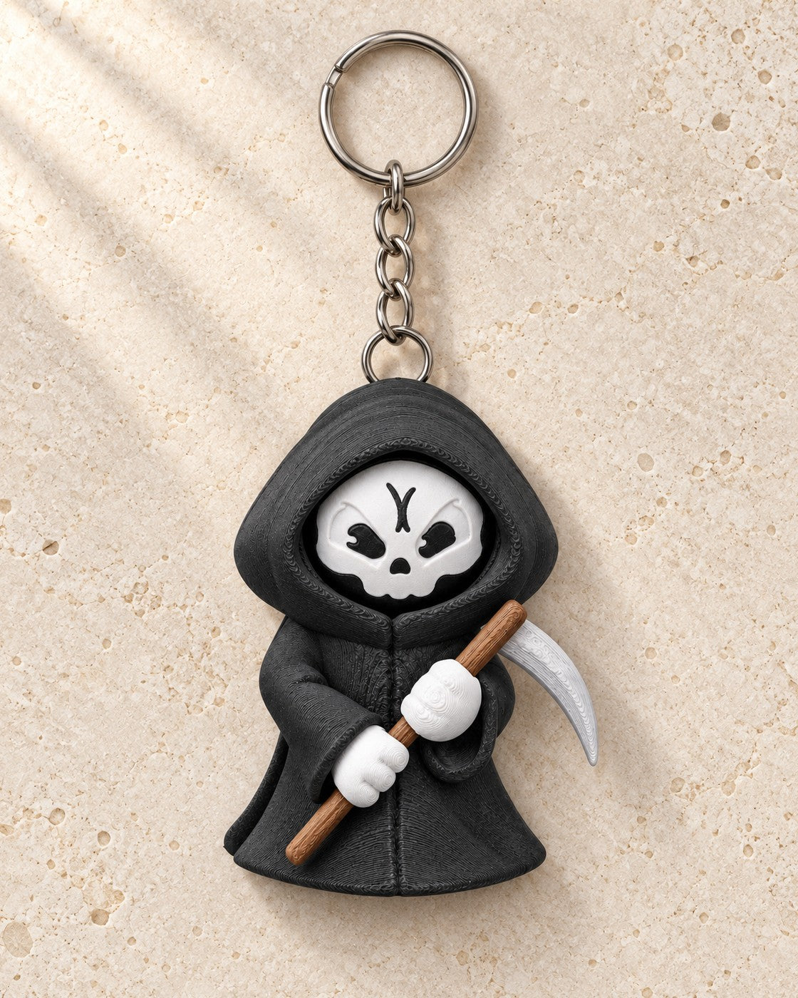 Moody Reaper Keyring on a pale limestone plinth, soft studio light