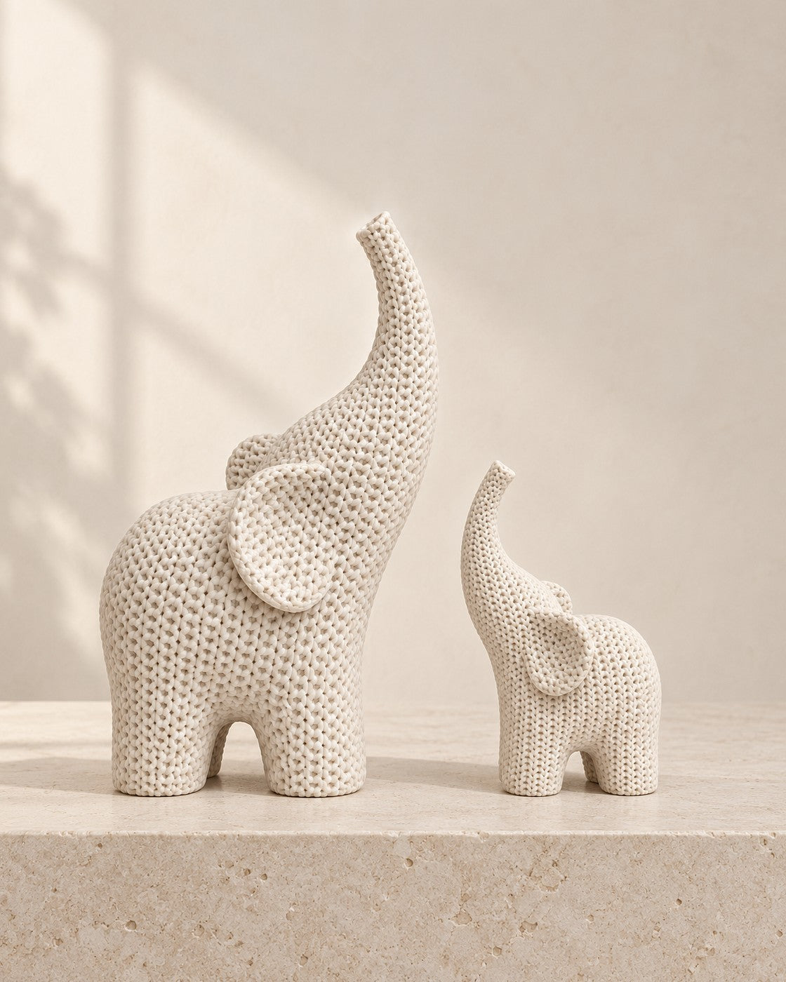 Knitted Elephant Pair on a pale limestone plinth, soft studio light