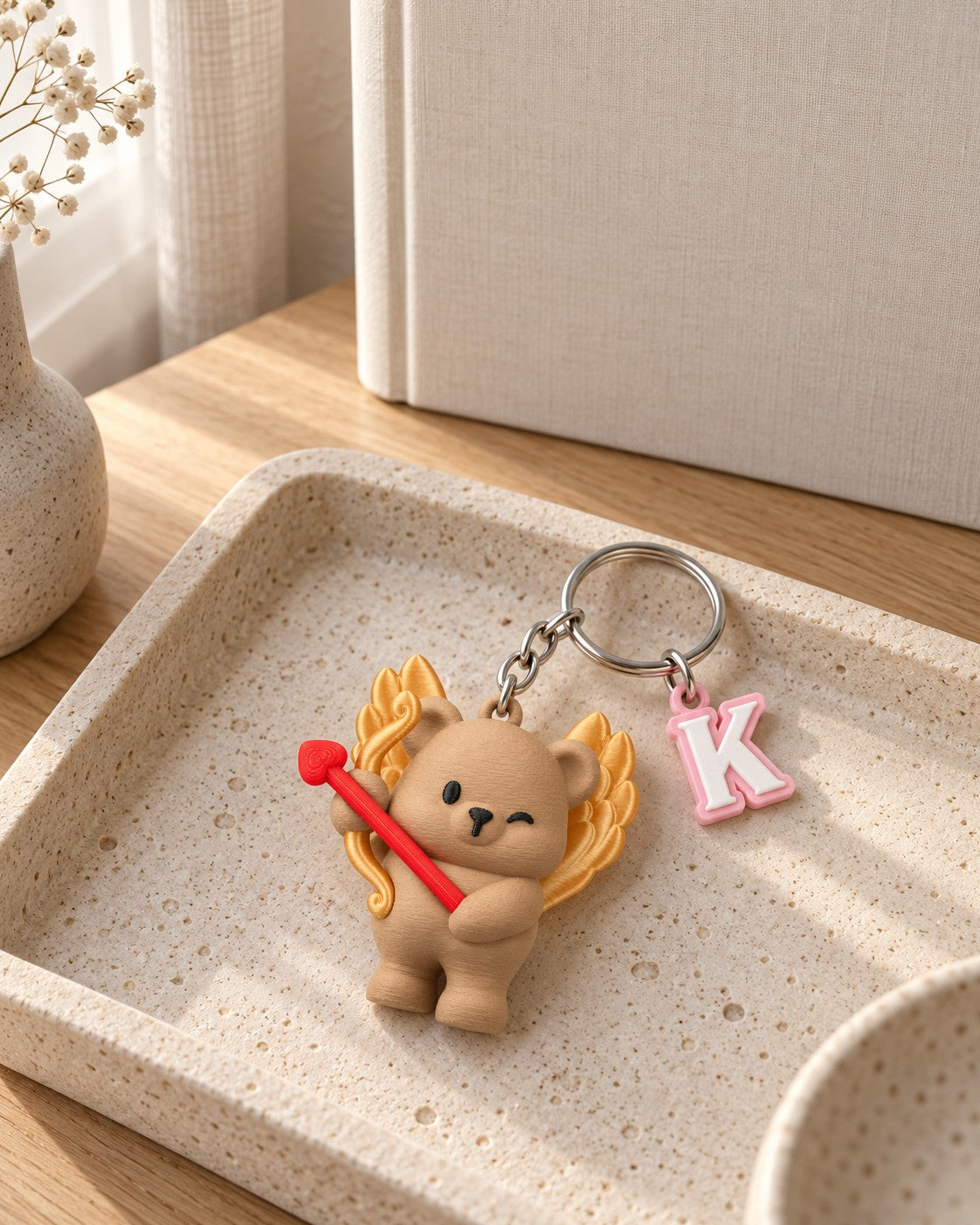 Cupid Cub Initial Keyring in a calm, softly lit interior, shown at true scale