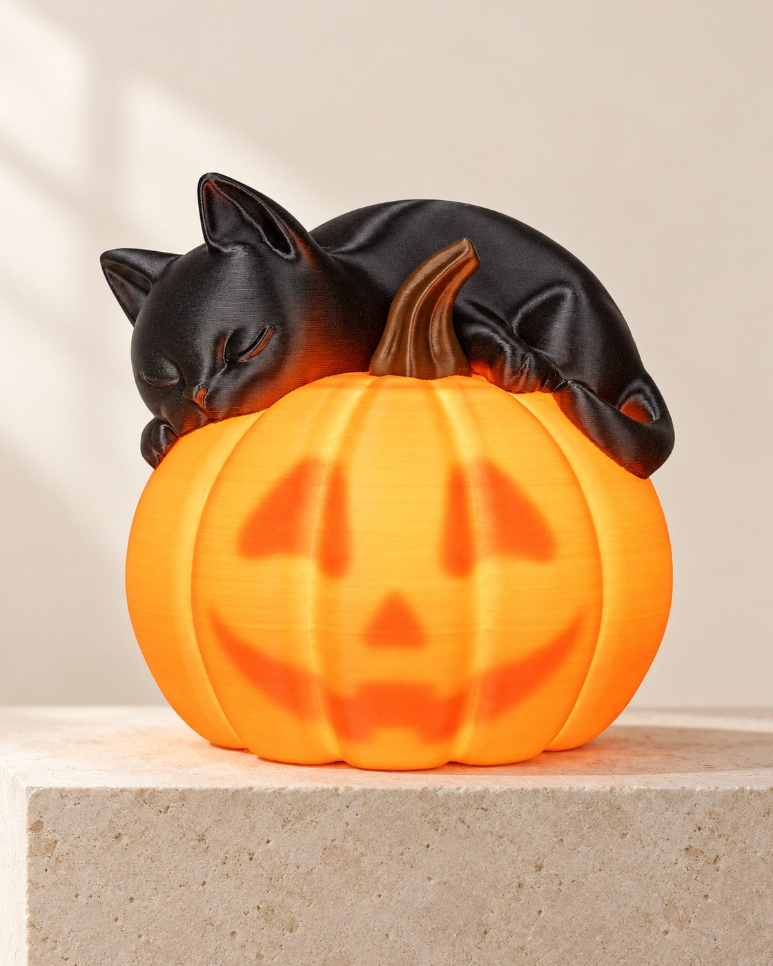 Sleepy Cat Pumpkin Lamp on a pale limestone plinth, soft studio light