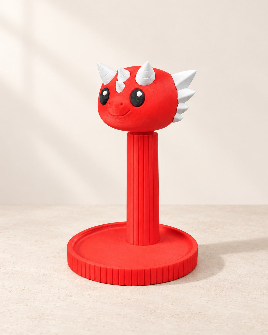 Red dragon headphone stand with white horns and black eyes, front view on a cream background