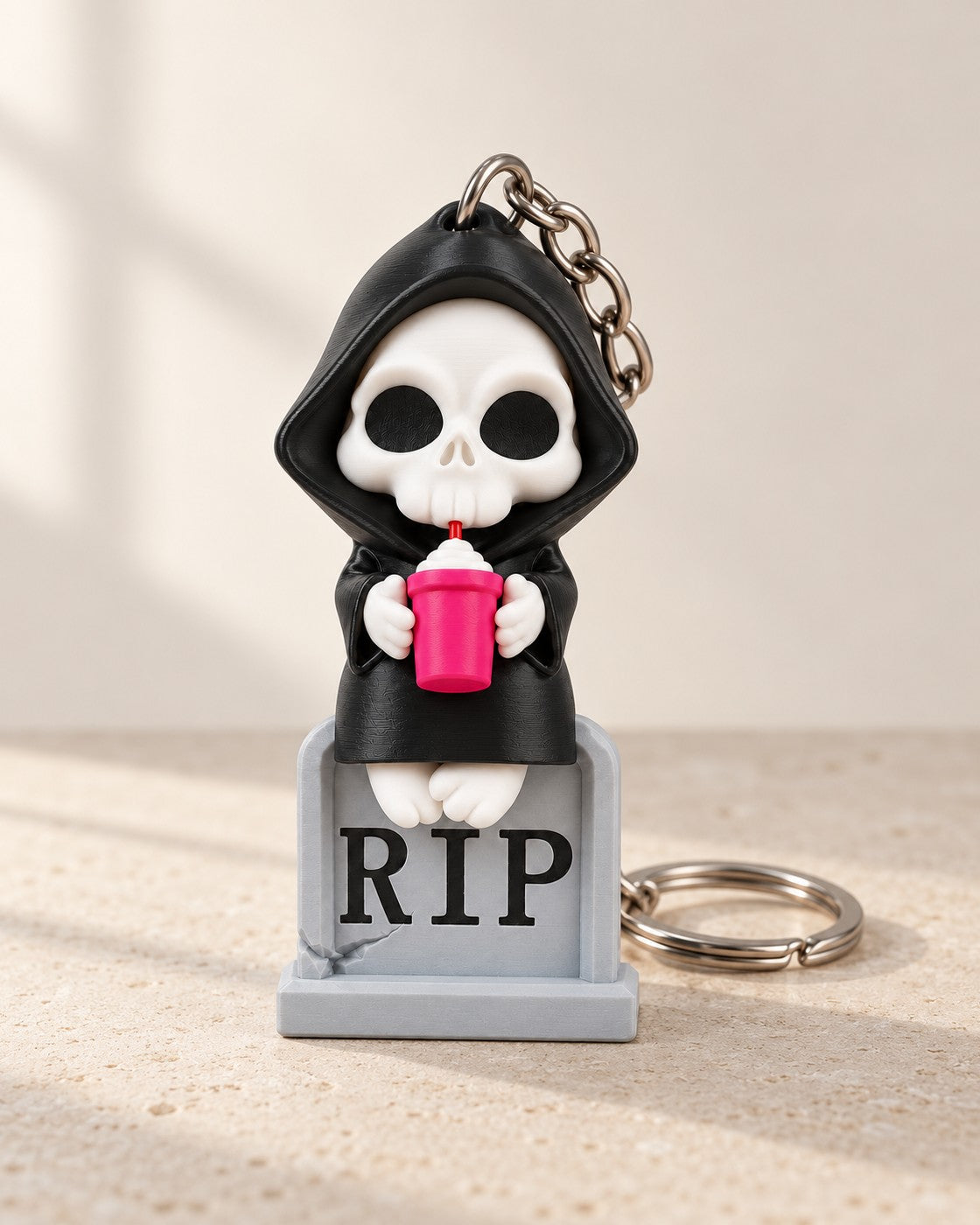 Sweet Rest Reaper Keyring on a pale limestone plinth, soft studio light
