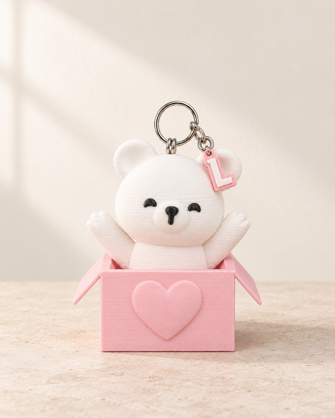 Peek-a-Bear Initial Keyring on a pale limestone plinth, soft studio light