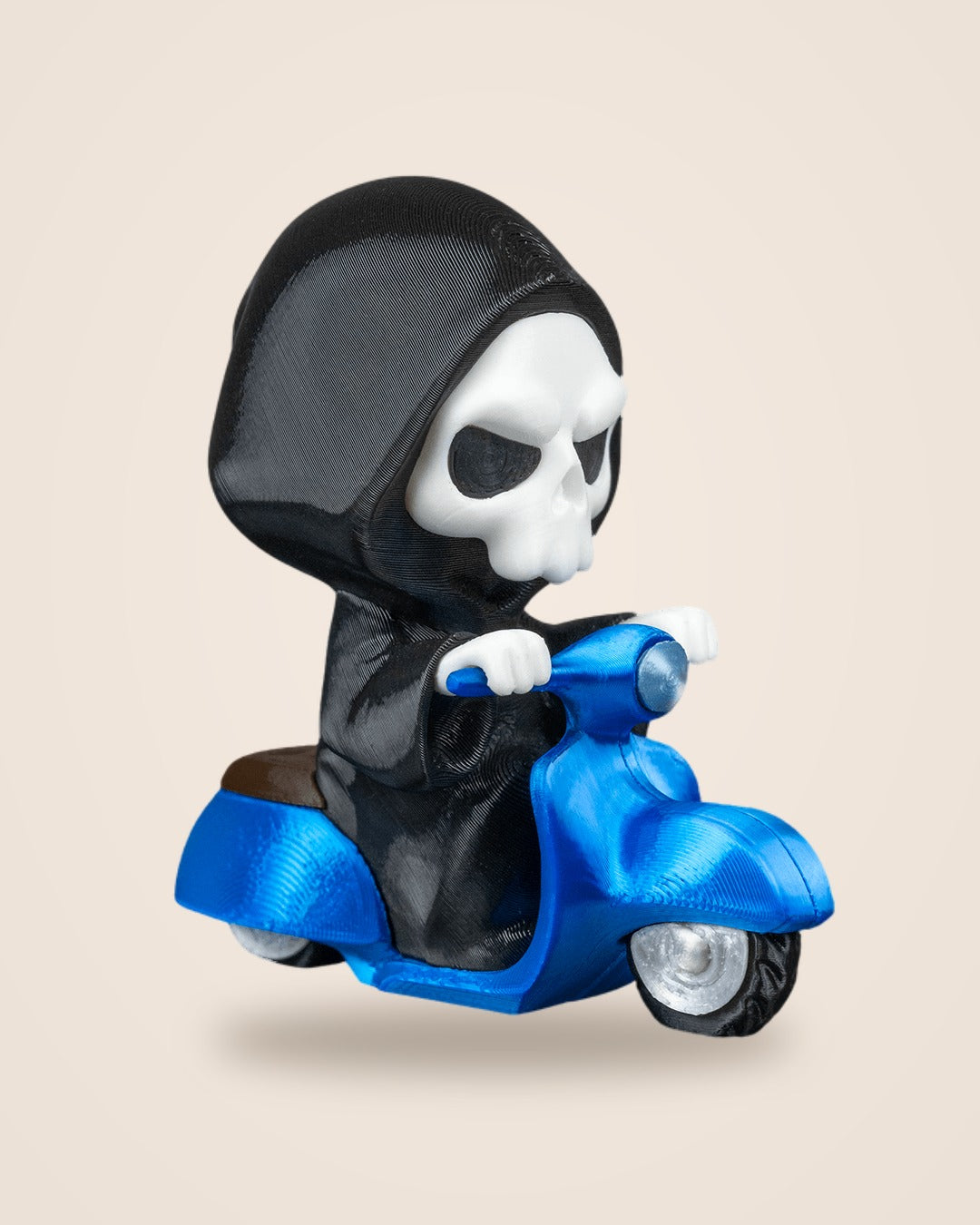 Three-quarter view of a Grim Reaper figurine on a blue scooter with a brown saddle and silver wheel hubs
