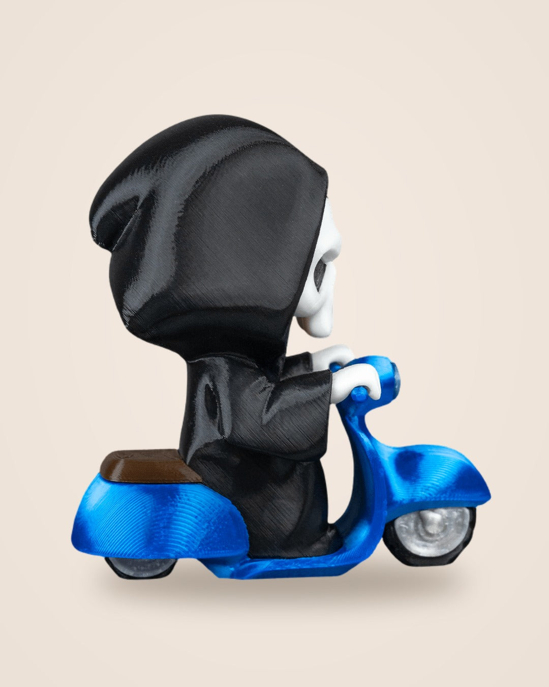 Side profile of a black-robed Grim Reaper figurine seated on a glossy blue scooter